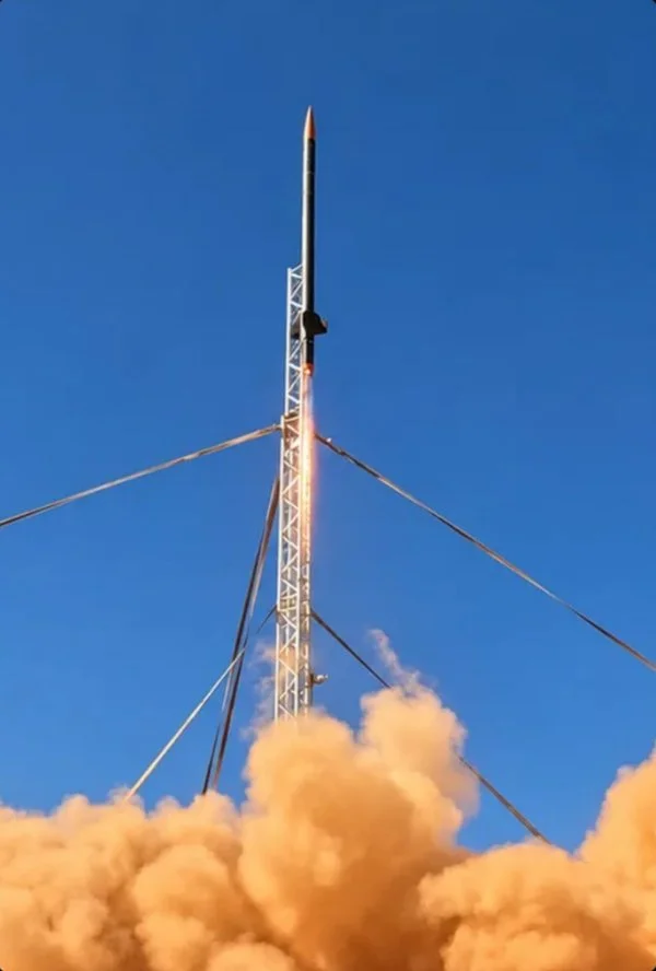 Rocket clearing the launch tower in a cloud of orange dust